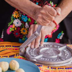 woman with traditional clothes pressing tortilla press in Mexico